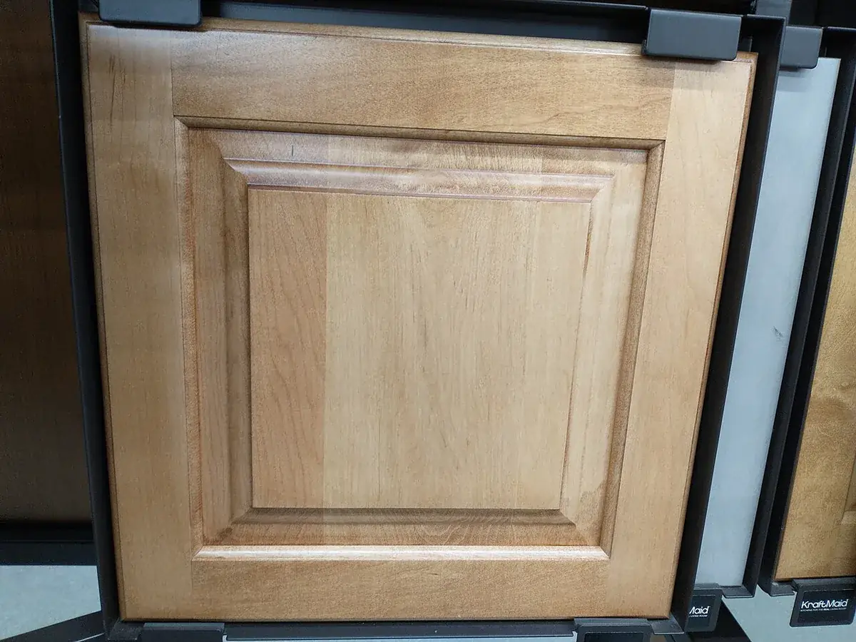Raised panel maple cabinet door sample hung on a showroom display rack next to other door styles