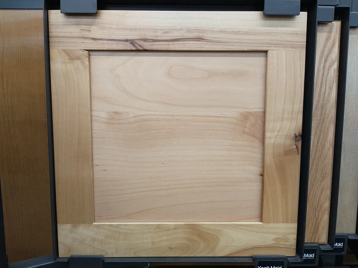 Shaker style maple cabinet door sample on a showroom display rack alongside other door styles