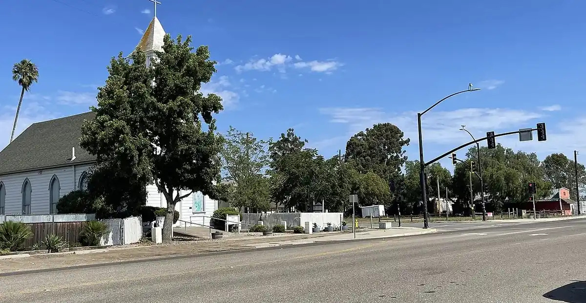 A white timber church and roadside in Nipomo CA under a clear sky, in the San Luis Obispo County part of the Santa Maria Valley