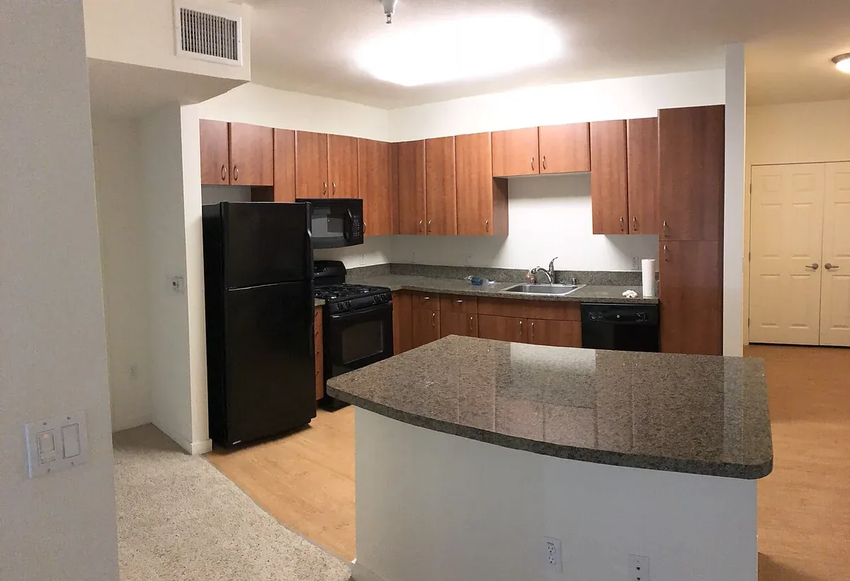 Builder grade cherry finished kitchen cabinets with a granite topped peninsula, the kind of kitchen commonly upgraded or refaced in Lompoc CA