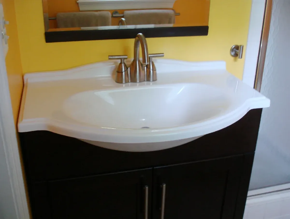 Dark espresso finished bathroom vanity base with an integrated white counter and basin and brushed nickel handles